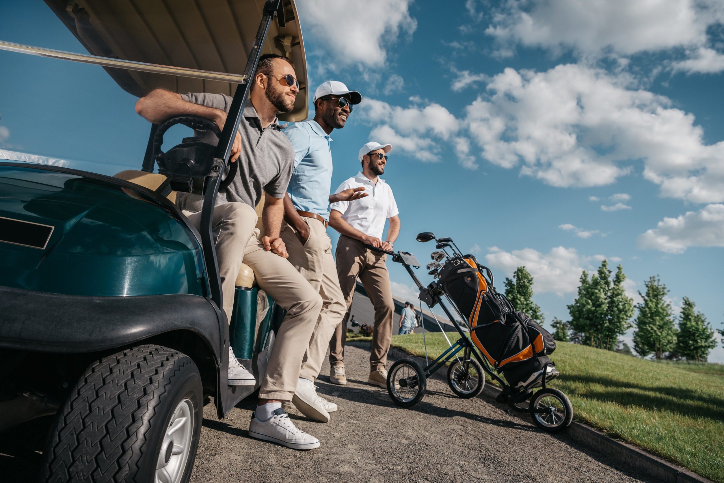 selective focus of happy mature friends with golf cart on golf course<br />
